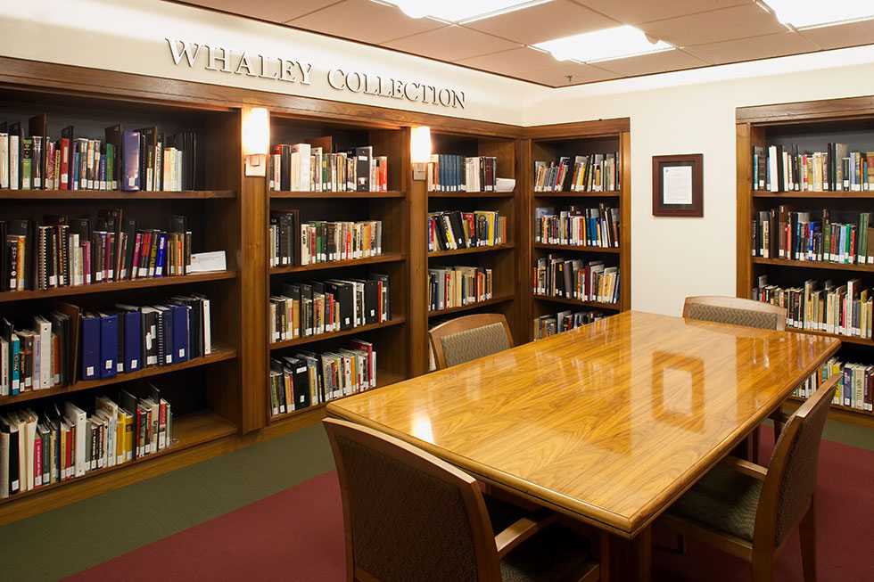 Full bookshelves next to a wooden table with 4 chairs.